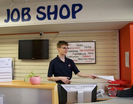 A student hands out a leaflet at the QAC Job Shop desk