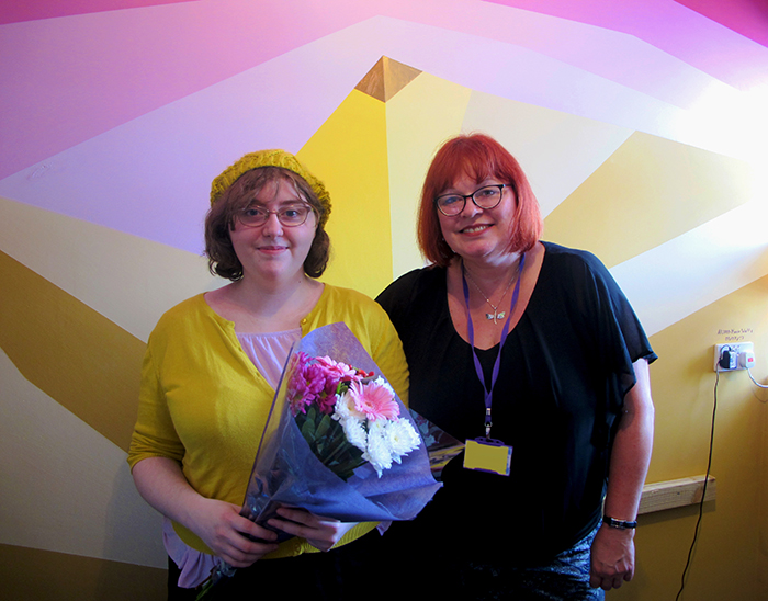 Alison holding a bouquet of flowers, posing for photo with Vice Principal Bev