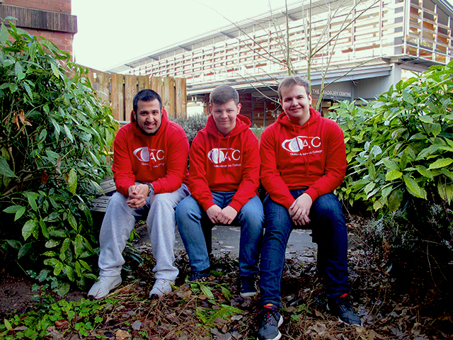 Student ambassadors Hamza, Will and Josh sitting on a bench with a leafy surrounding.