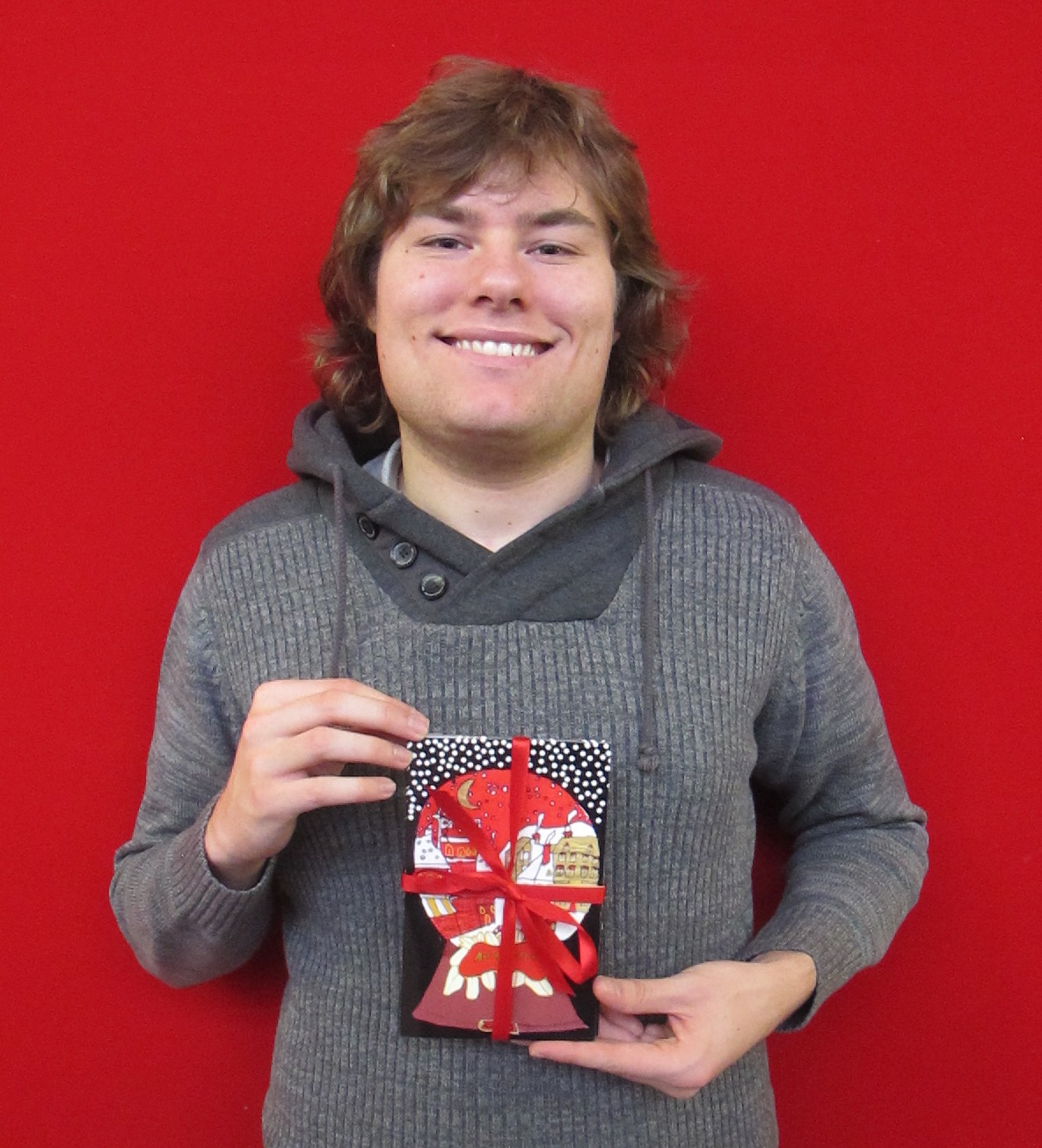 Student holds QAC Christmas card for 2015 