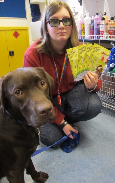 Beth holds QAC Christmas cards for 2017 with Rufus, College Buddy Dog