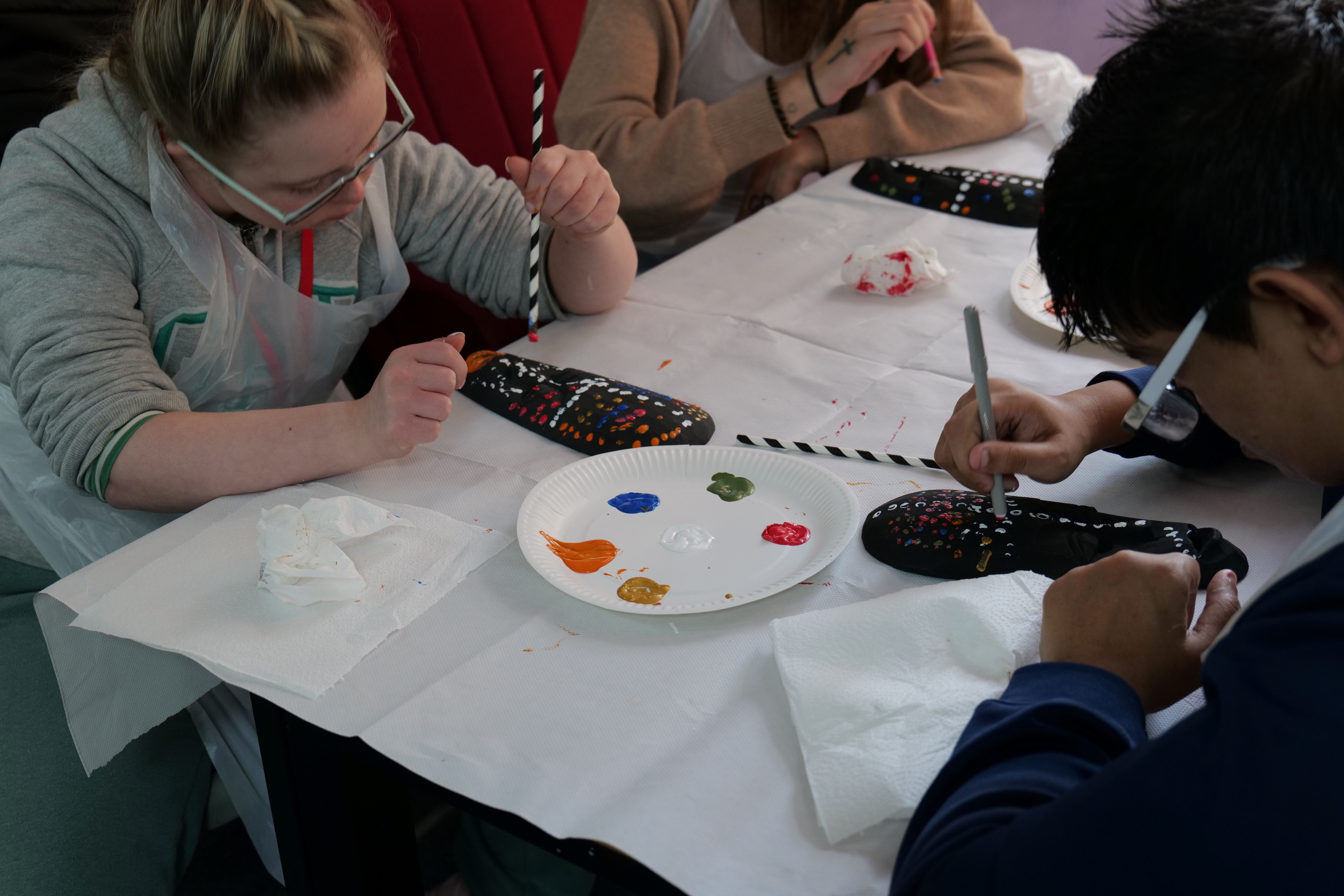 Two students painting a mask