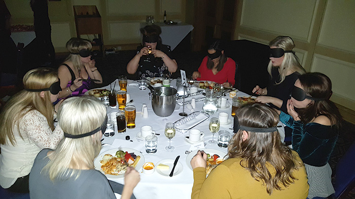 Group of blindfolded diners enjoying their meal at Dinner in the Dark