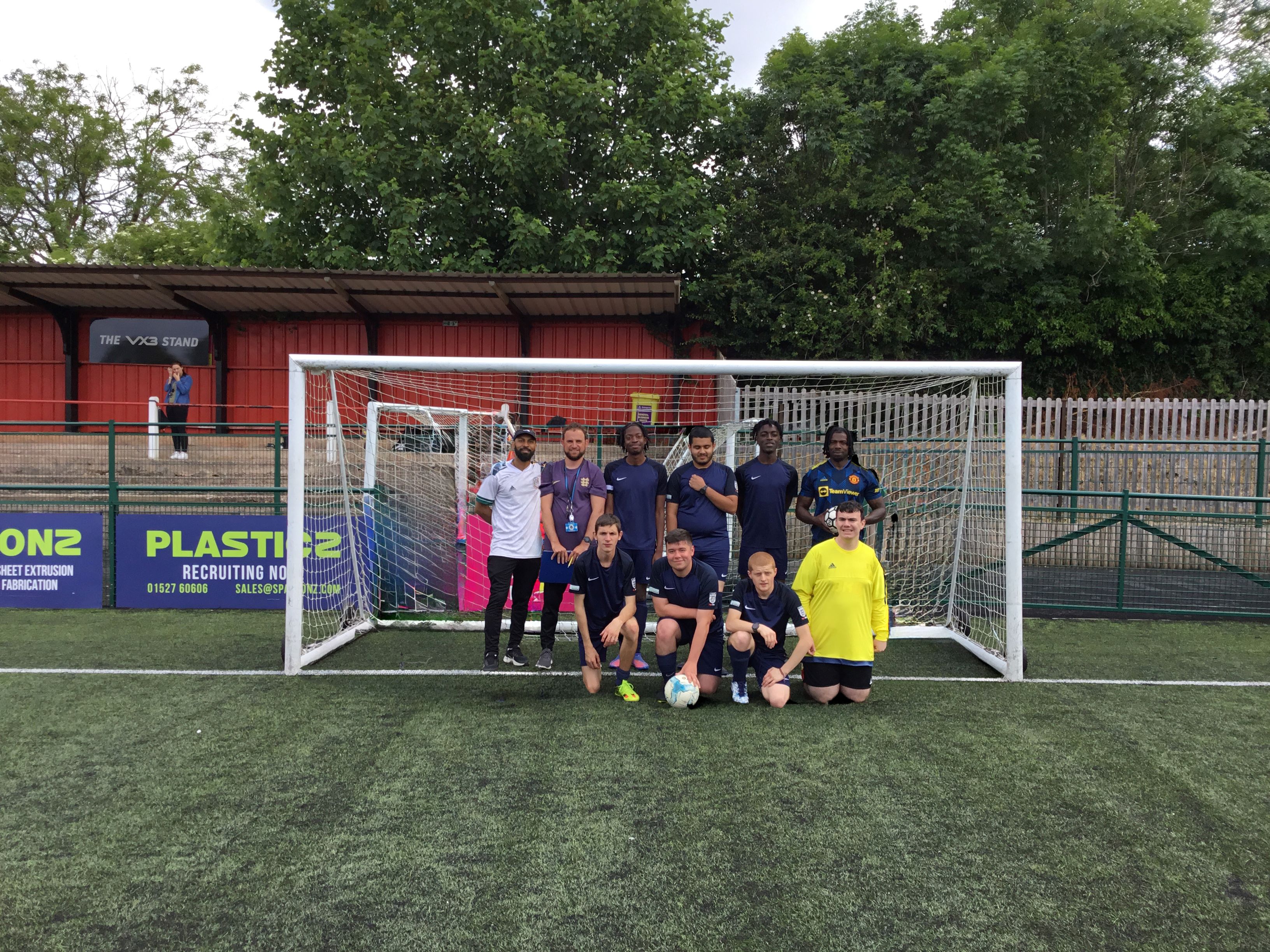 QAC football team smiling for a photo on the pitch