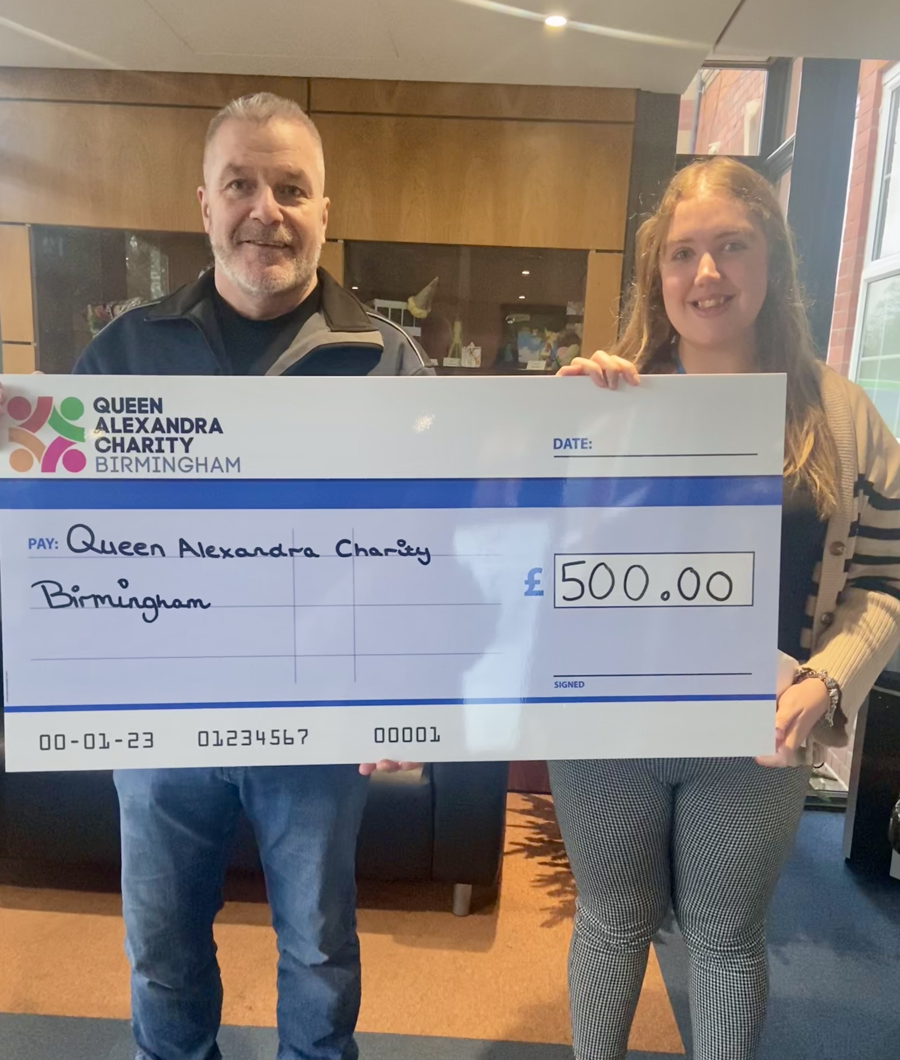 Barry and Pippa holding a large cheque with £500 and smiling at the camera