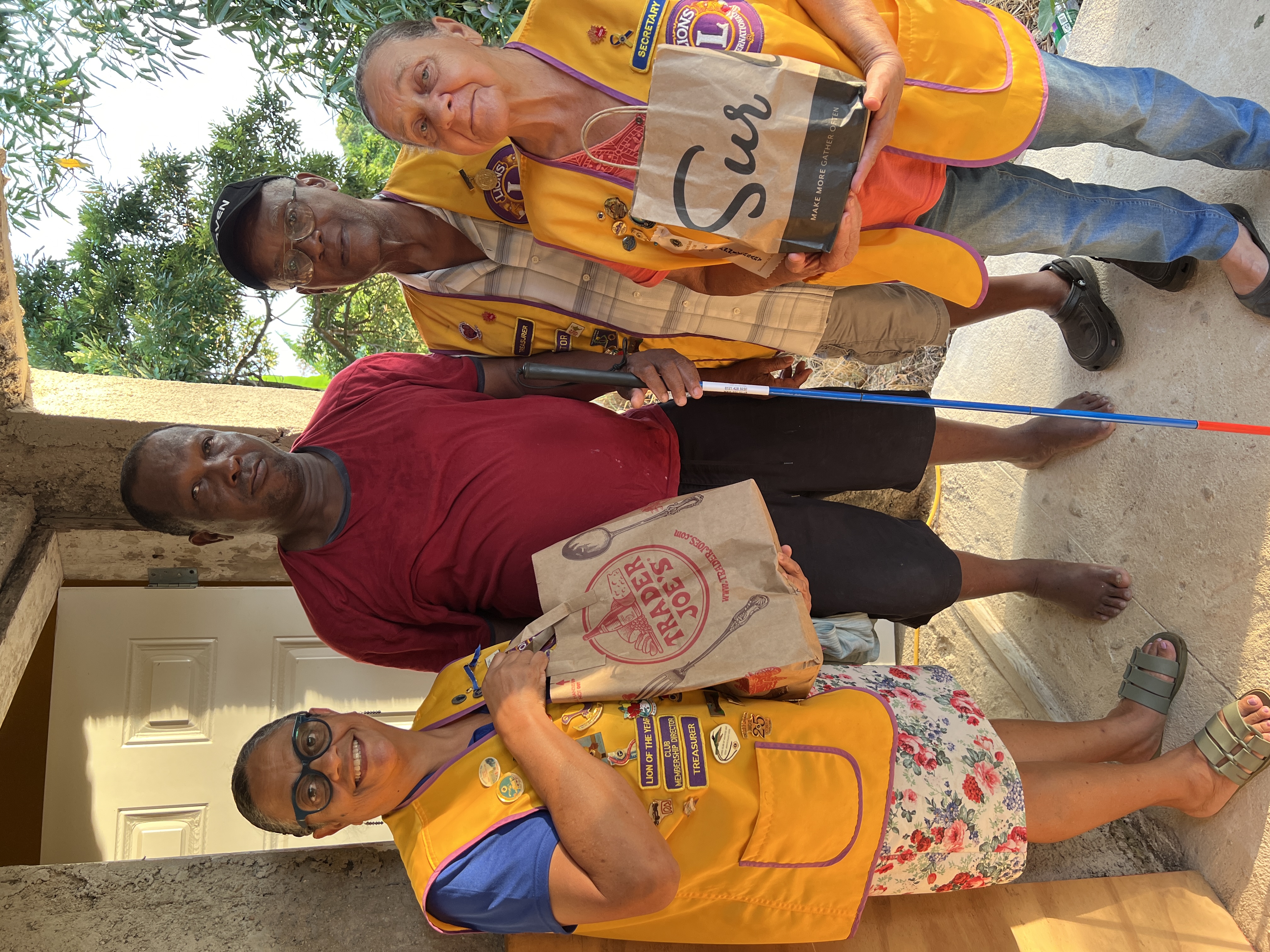 Image of Three members of the St. Lions club stood with a citizen holding a cane