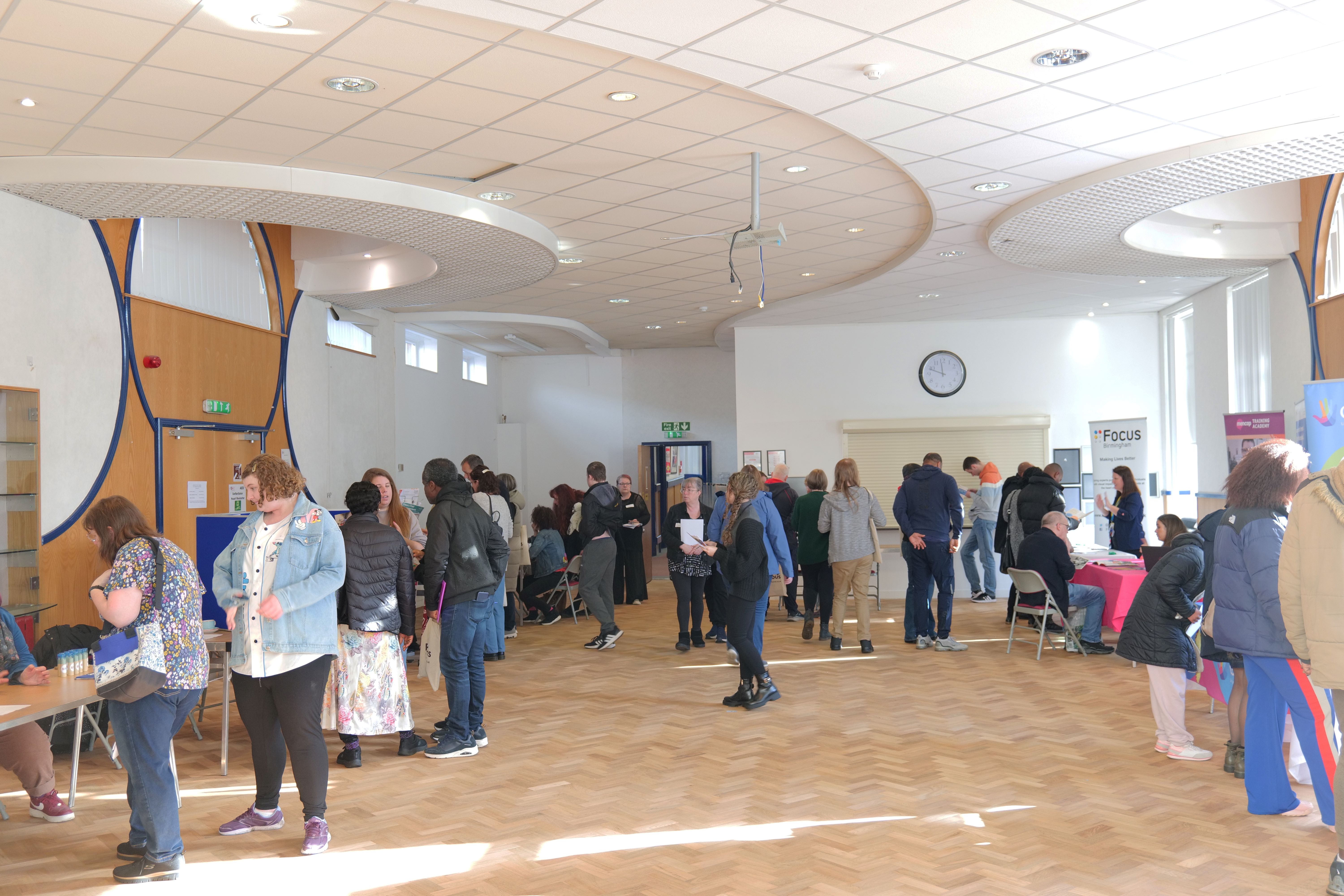 Image of students and their families walking around the hall talking to exhibitors