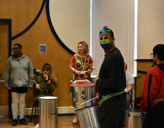 QAC students playing Samba music, one wearing a mask, during Mardi Gras celebrations