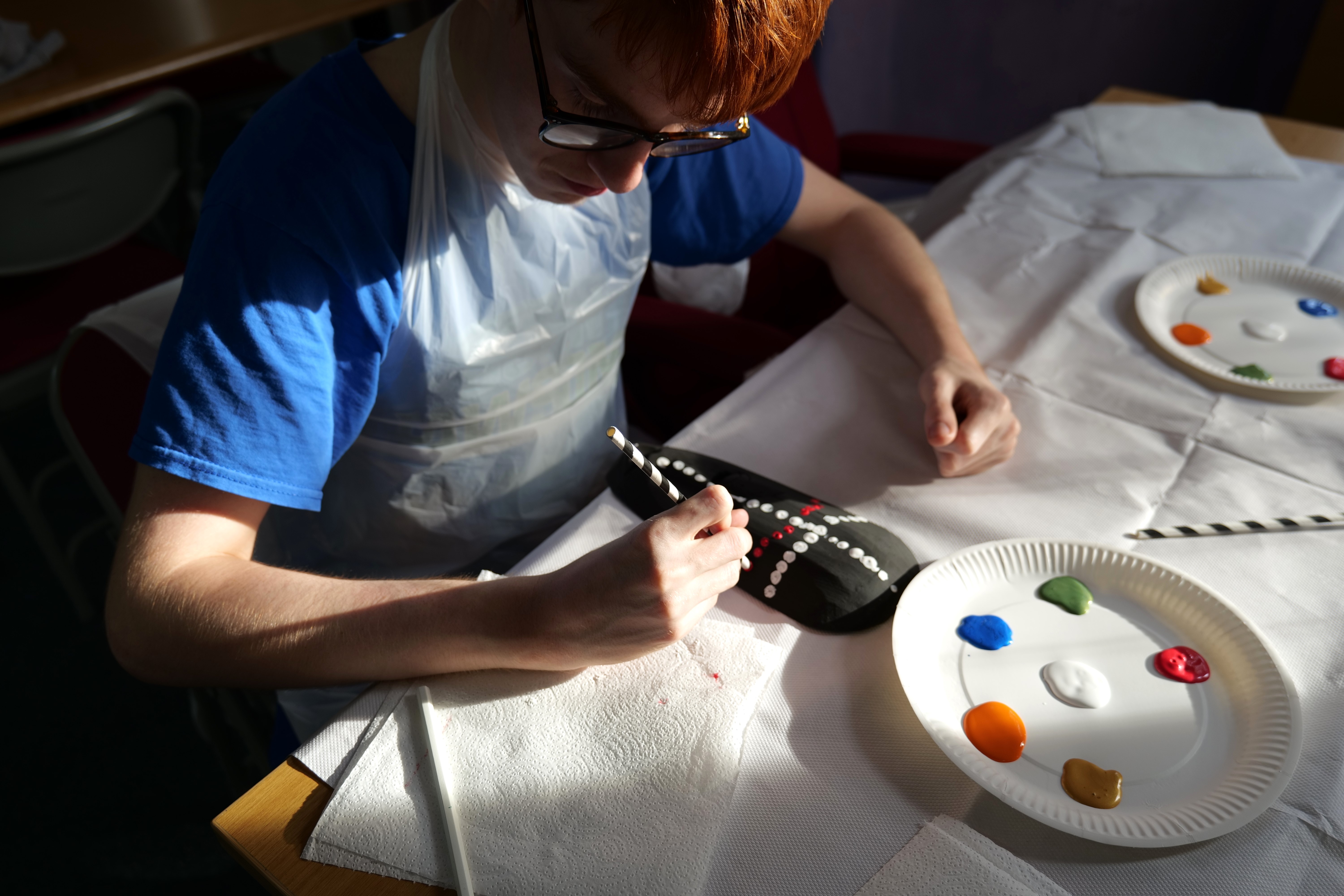 Student painting a mask with red dots