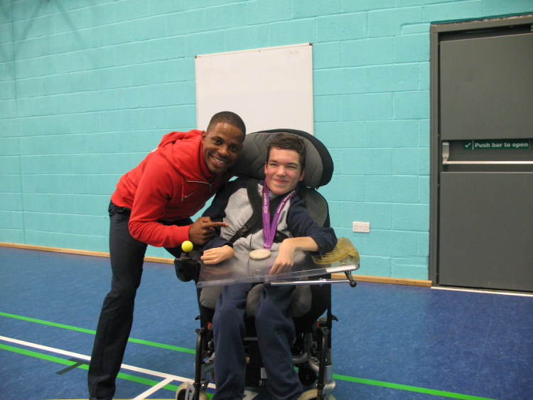 Mikail and QAC Student pose for photo with Mikail's Paralympic Silver Medal