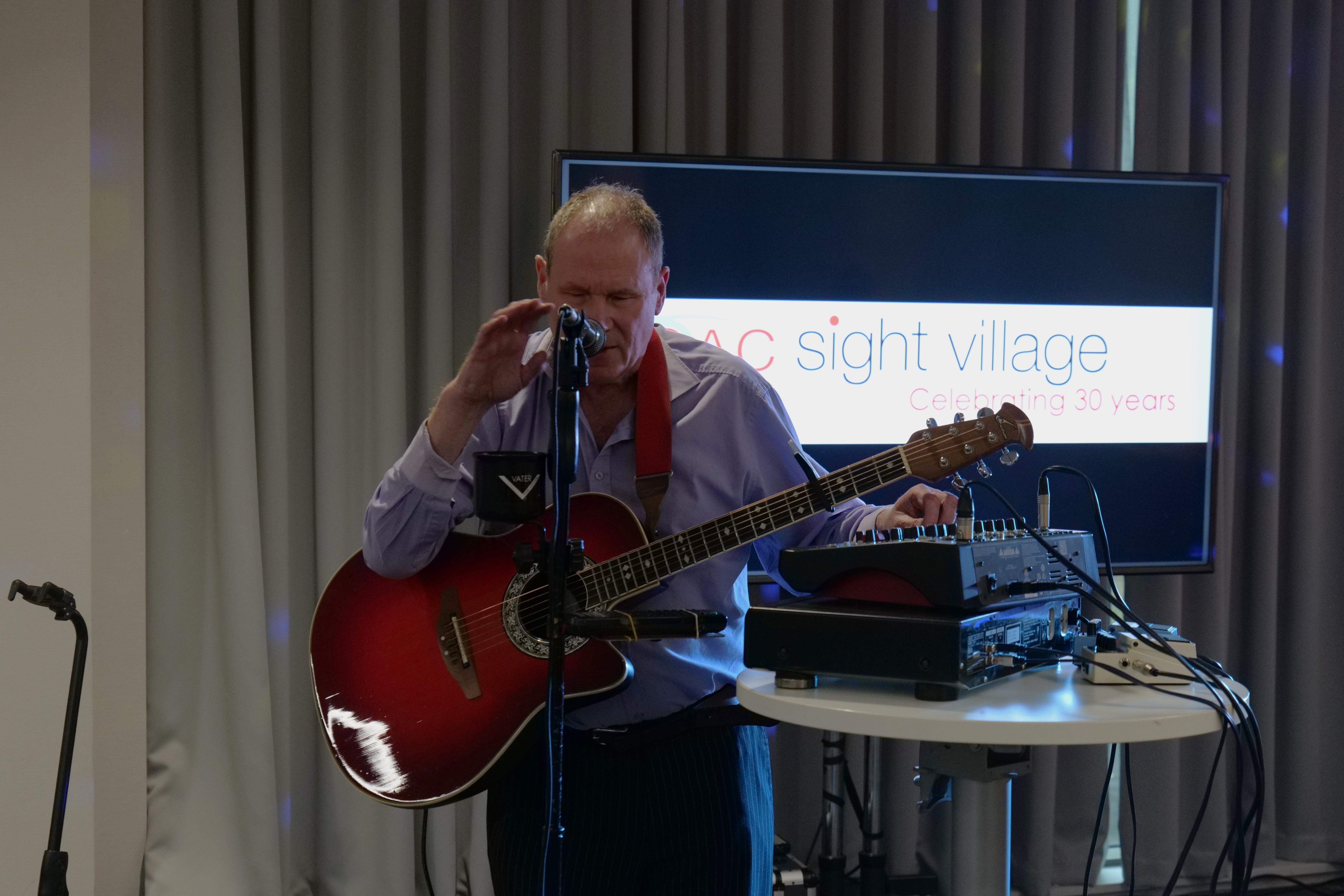 Carl Morgan singing and holding a guitar