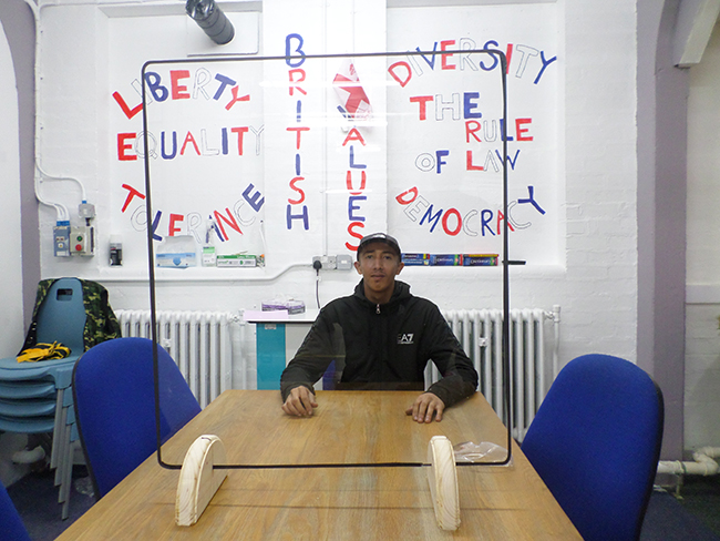 A students sits behind the finished protective screen!