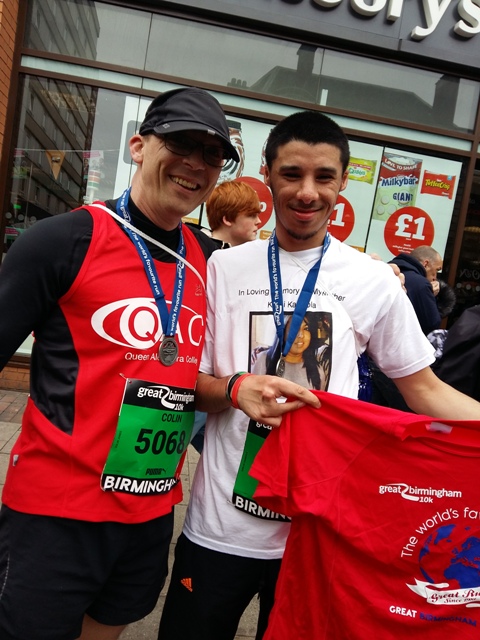 QAC student, Sanjay, proudly shows off his t-shirt and medal at the finish line alongside a QAC member of staff