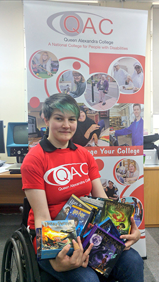 QAC Student Ruth holding up some of the items donated by J.K. Rowling