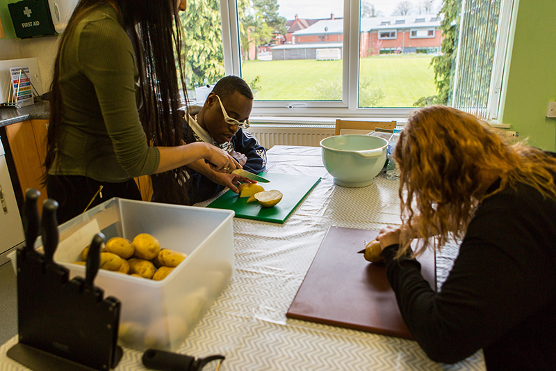 Residential staff support students preparing a meal 